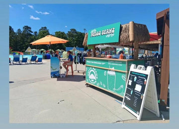 Outdoor food stand with 'Melo Beans' branding in a park-like setting. Oceanbreeze Water park, Virginia Beach, Virginia. Cold Brew.